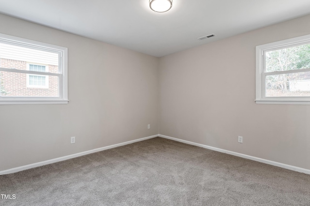 carpeted empty room featuring baseboards and visible vents