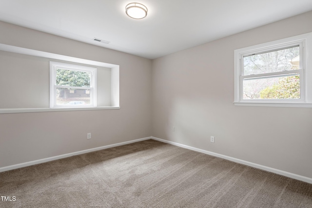 carpeted empty room featuring visible vents and baseboards