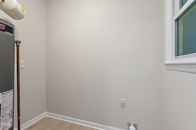 laundry room with light wood-type flooring, gas water heater, baseboards, hookup for an electric dryer, and laundry area