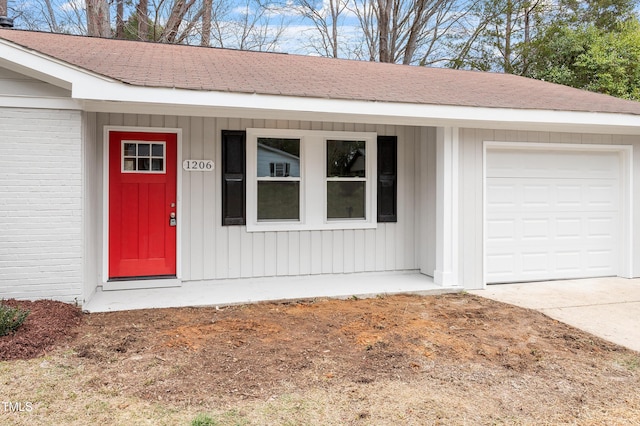 view of exterior entry featuring brick siding, board and batten siding, concrete driveway, and an attached garage