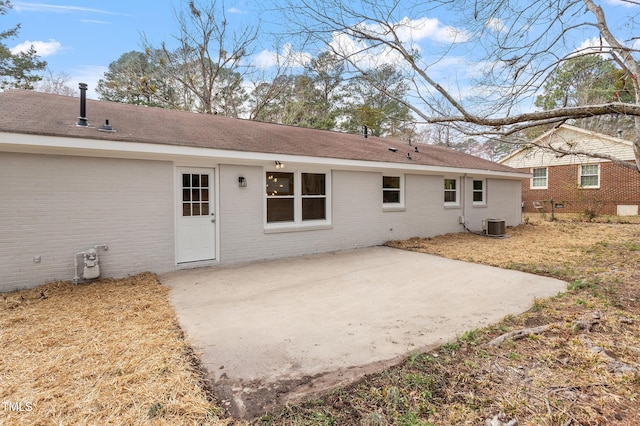 back of property with brick siding, central AC unit, and a patio