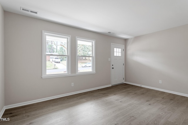 foyer with wood finished floors, visible vents, and baseboards