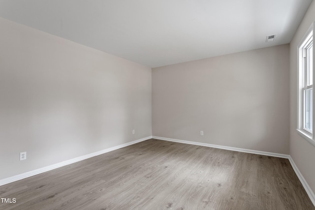 unfurnished room with visible vents, baseboards, and wood finished floors