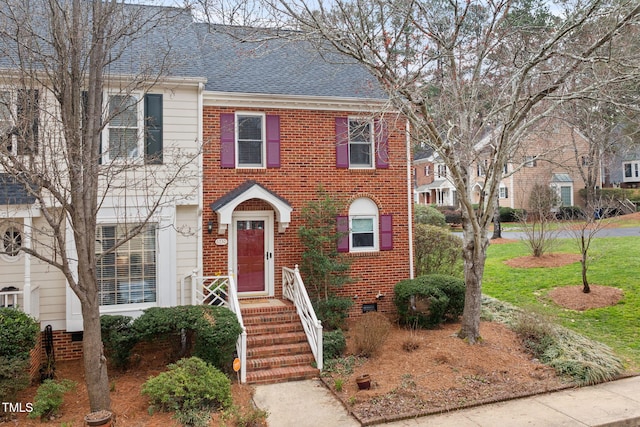 view of front facade with crawl space, brick siding, and roof with shingles