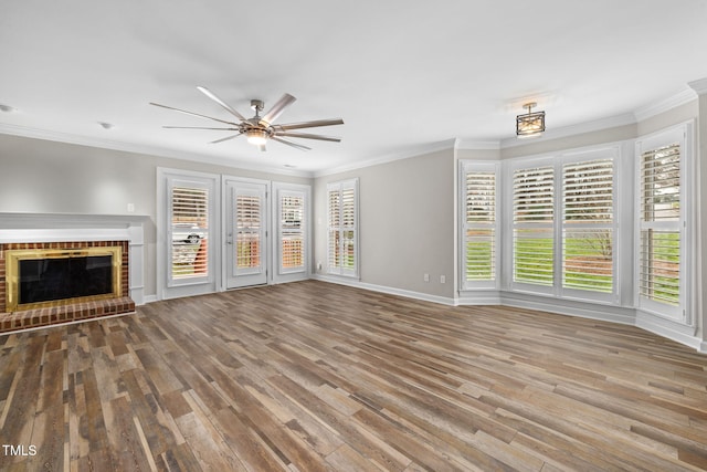 unfurnished living room featuring crown molding, a brick fireplace, and wood finished floors