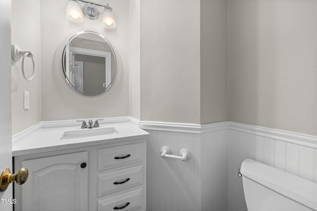 bathroom featuring vanity, toilet, and wainscoting