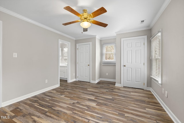 unfurnished bedroom featuring visible vents, ornamental molding, ensuite bathroom, wood finished floors, and baseboards