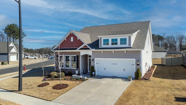 craftsman-style house with concrete driveway, an attached garage, fence, and a shingled roof