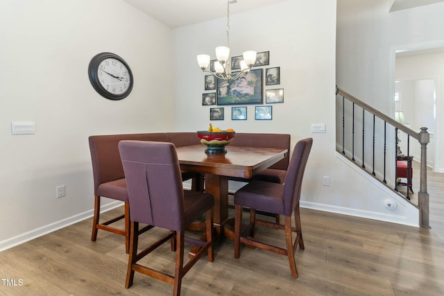 dining room featuring a chandelier, stairway, baseboards, and wood finished floors