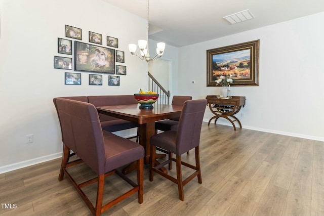 dining space with light wood-style flooring, a notable chandelier, visible vents, and baseboards