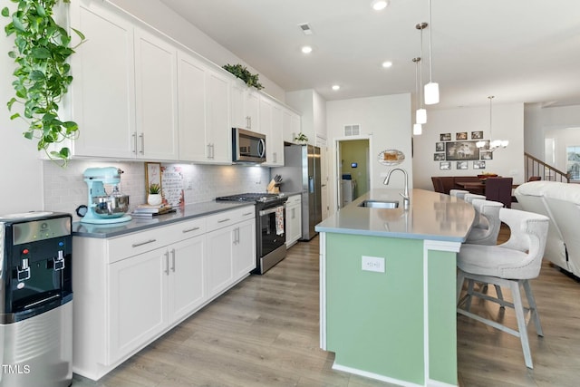 kitchen featuring a kitchen bar, decorative backsplash, an inviting chandelier, stainless steel appliances, and a sink