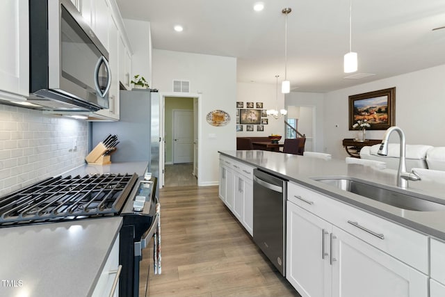 kitchen featuring visible vents, light wood-style flooring, a sink, appliances with stainless steel finishes, and white cabinetry