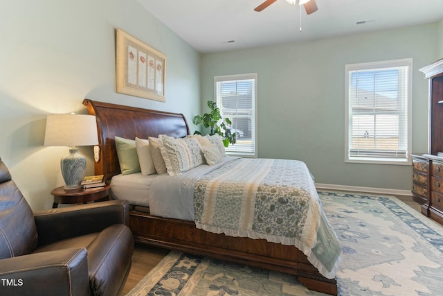 bedroom featuring ceiling fan, visible vents, baseboards, and wood finished floors