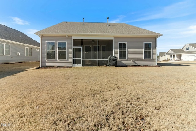 back of house featuring a lawn, roof with shingles, and a sunroom