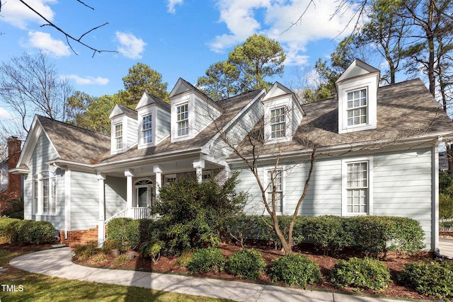 cape cod home with a porch and a shingled roof