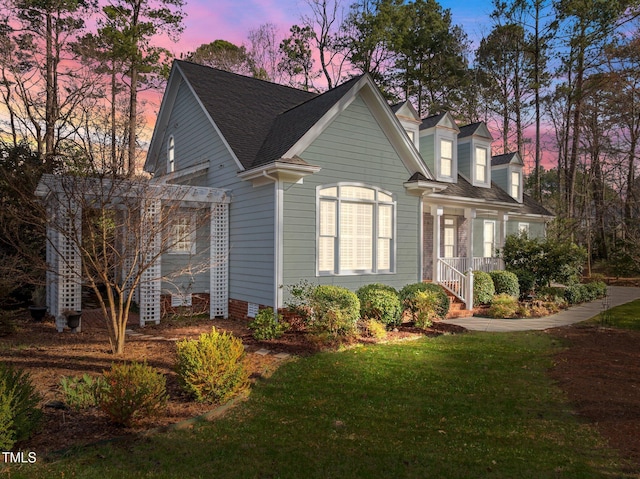 view of front of home featuring a yard and a shingled roof