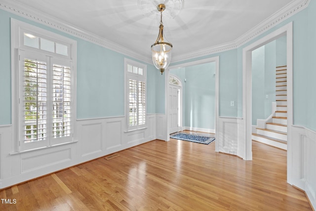 foyer featuring stairway, visible vents, light wood-style flooring, and ornamental molding