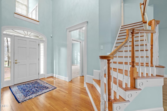 entryway with stairs, a high ceiling, wood finished floors, and baseboards