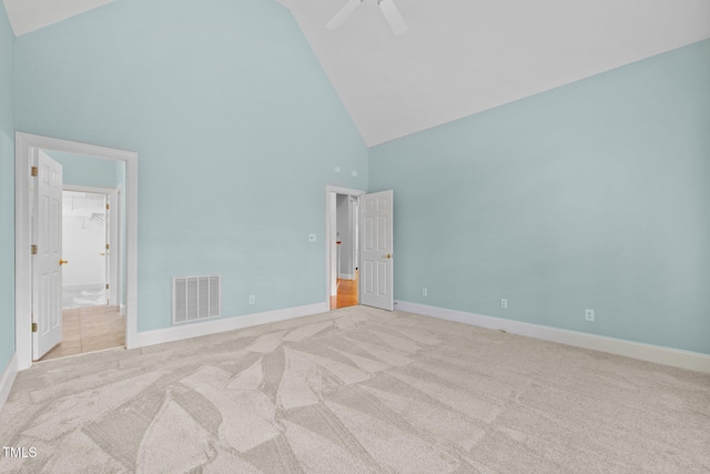 unfurnished bedroom with visible vents, connected bathroom, baseboards, light colored carpet, and high vaulted ceiling