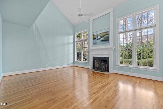 unfurnished living room featuring a fireplace with flush hearth, high vaulted ceiling, light wood-type flooring, and baseboards