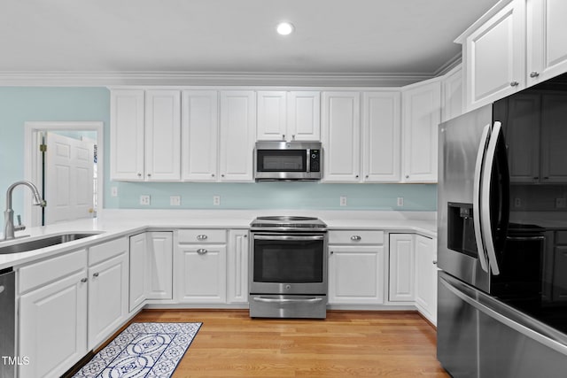 kitchen with light wood-type flooring, ornamental molding, a sink, white cabinetry, and appliances with stainless steel finishes