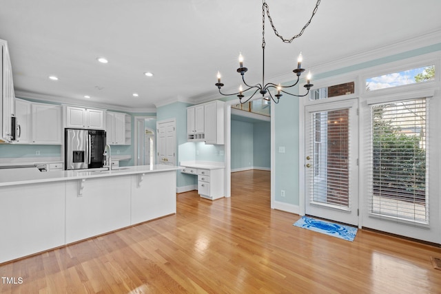 kitchen with white cabinetry, stainless steel appliances, light countertops, and ornamental molding