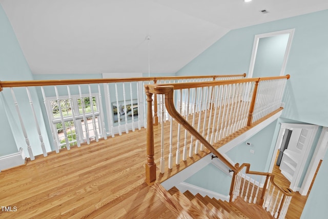 stairs with wood finished floors and vaulted ceiling