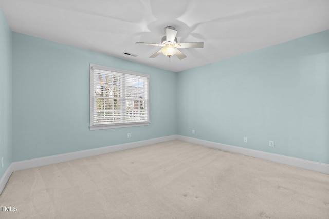 carpeted spare room with visible vents, baseboards, and ceiling fan