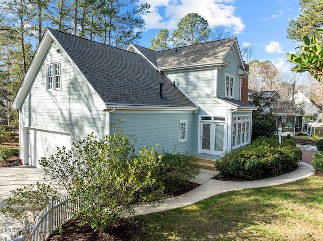 view of side of property featuring a garage and roof with shingles