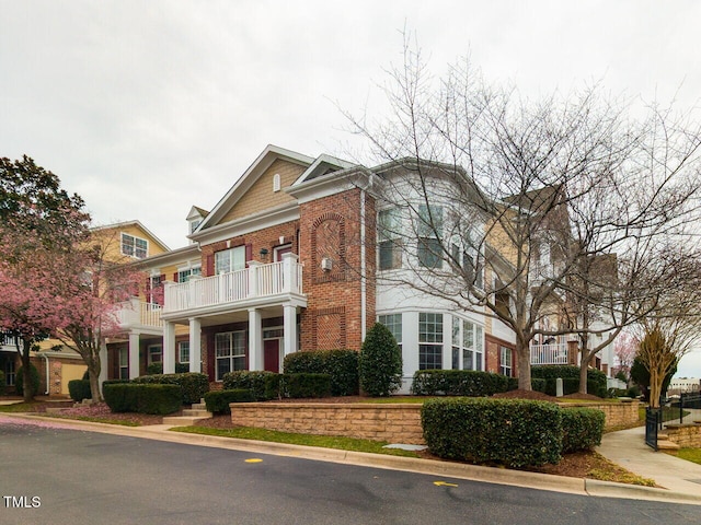 view of front of house featuring a balcony and brick siding