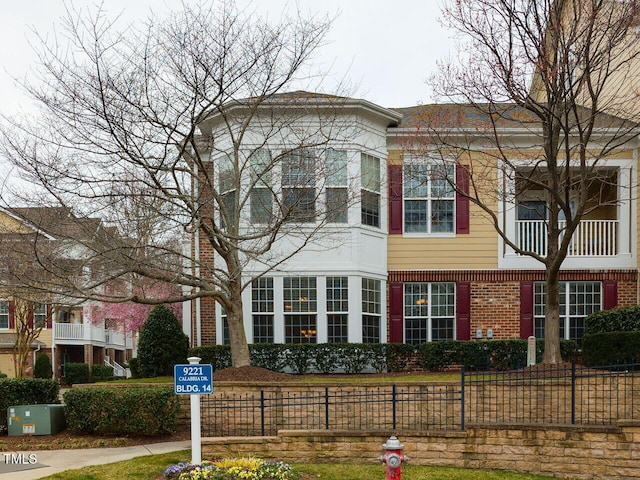 multi unit property with brick siding and a fenced front yard