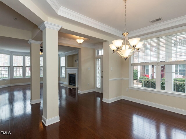 unfurnished dining area featuring visible vents, ornate columns, a fireplace, dark wood-type flooring, and crown molding