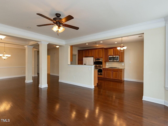 unfurnished living room featuring ceiling fan with notable chandelier, dark wood-style floors, crown molding, baseboards, and ornate columns