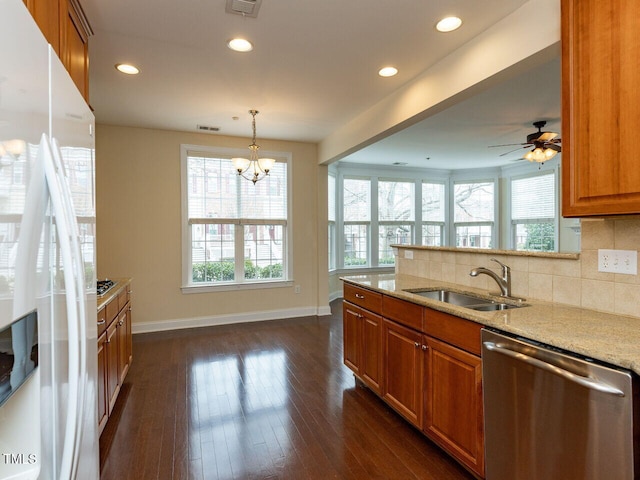 kitchen with a sink, brown cabinets, white fridge with ice dispenser, and stainless steel dishwasher