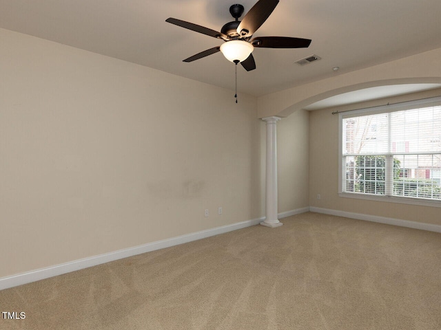 spare room featuring decorative columns, light colored carpet, visible vents, and baseboards