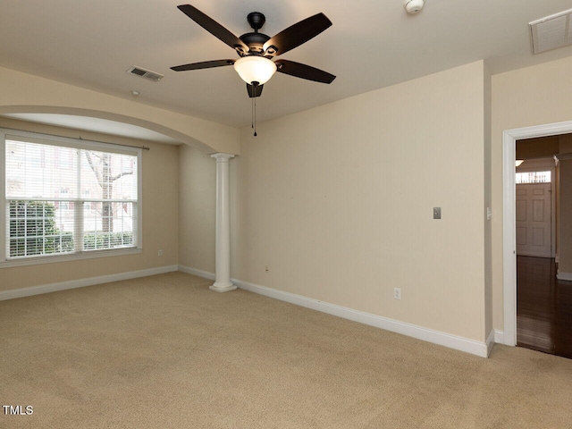 unfurnished room featuring light colored carpet, visible vents, ornate columns, and arched walkways