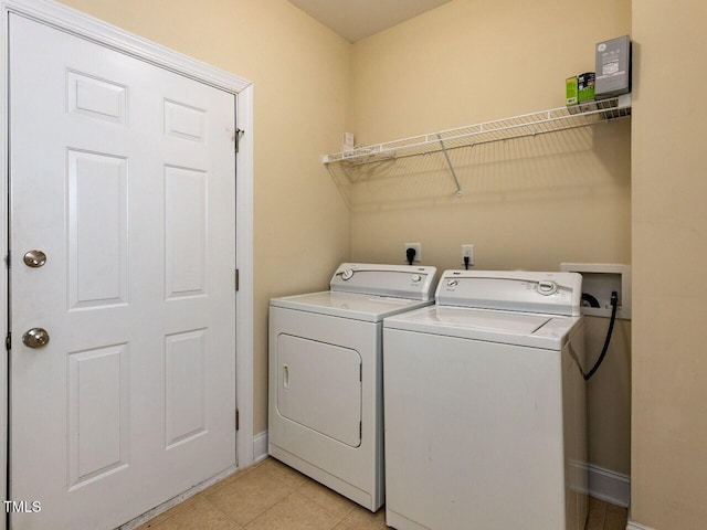 laundry room featuring laundry area, light tile patterned flooring, baseboards, and washer and clothes dryer