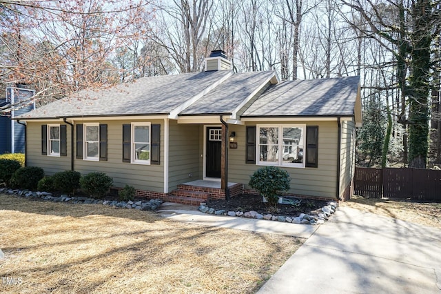 single story home featuring a chimney, roof with shingles, and fence