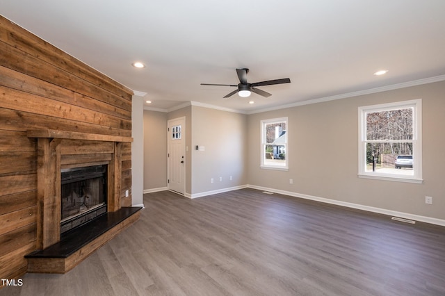 unfurnished living room with baseboards, a large fireplace, dark wood finished floors, and crown molding