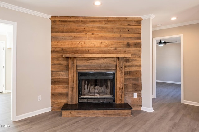 interior details with wood finished floors, a fireplace with raised hearth, and ornamental molding