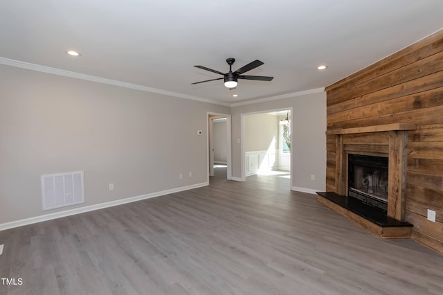 unfurnished living room featuring visible vents, crown molding, baseboards, a fireplace, and wood finished floors