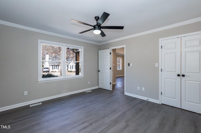 unfurnished bedroom with visible vents, baseboards, dark wood-style flooring, and crown molding