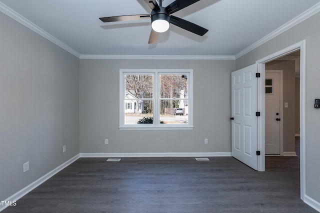 empty room featuring visible vents, dark wood-type flooring, ornamental molding, a ceiling fan, and baseboards