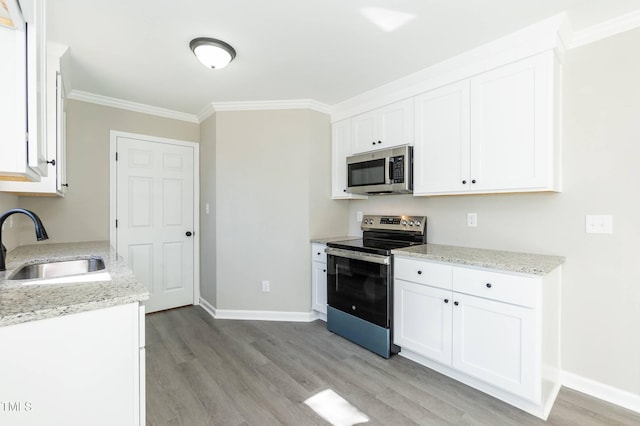 kitchen featuring light wood finished floors, a sink, stainless steel appliances, white cabinets, and crown molding