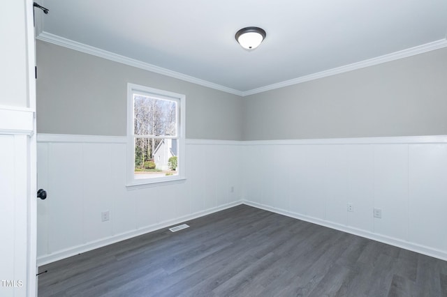 spare room with wainscoting, dark wood-type flooring, and ornamental molding