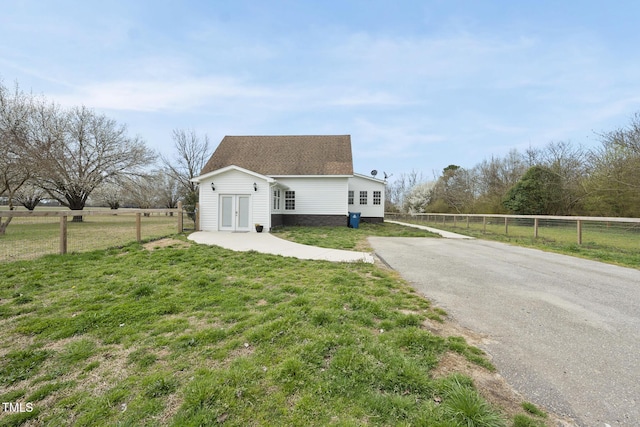 view of property exterior featuring roof with shingles, a yard, and fence