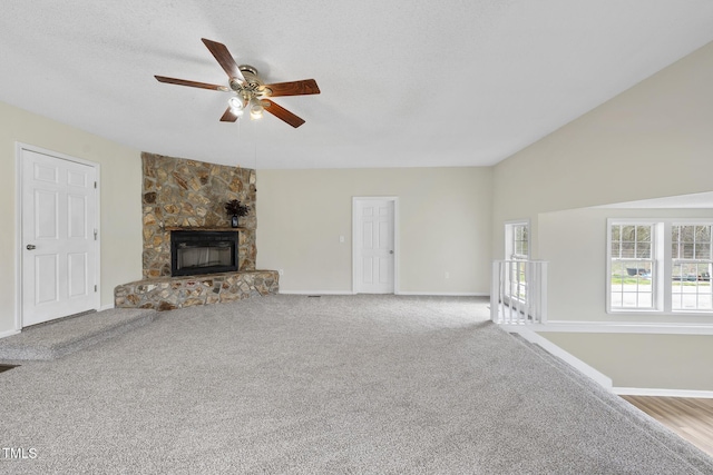 unfurnished living room featuring carpet, a ceiling fan, baseboards, a fireplace, and a textured ceiling