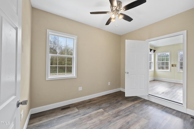 empty room featuring a ceiling fan, baseboards, and wood finished floors