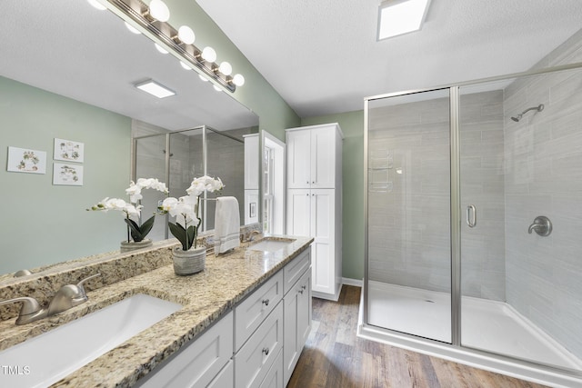 full bathroom with a shower stall, a textured ceiling, wood finished floors, and a sink