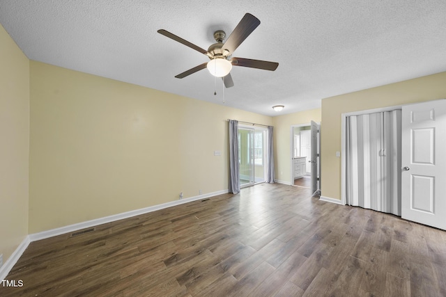 unfurnished bedroom featuring dark wood-type flooring, visible vents, baseboards, and a textured ceiling